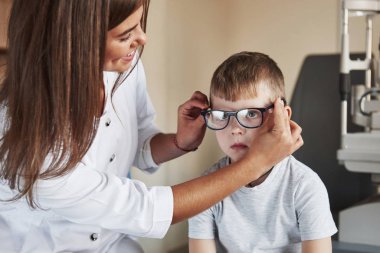 Güven bana, sana yardımı olacak. Çocuk doktor ofisinde oturuyor ve yeni mavi gözlükler deniyor..