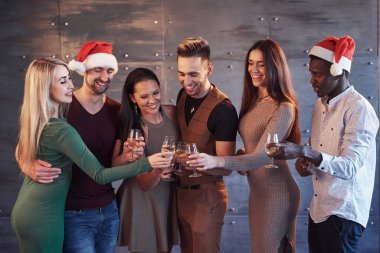 Yeni yıl geliyor! Partide Noel Baba şapkası takmış neşeli, çoklu etnik kökenli bir grup genç insan duygusal yaşam tarzı insanları konseptine poz veriyor..