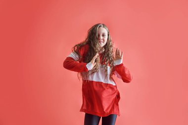 Genç ve güzel bir kız kırmızı arka planda dans ediyor, modern ince hip-hop stili genç kız atlıyor..