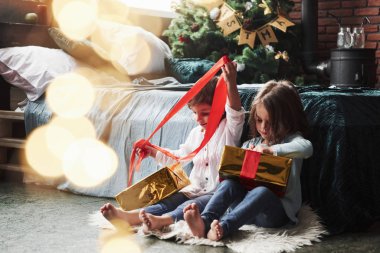 Sürpriz için hazırlan. Noel tatili ve yatağın yanındaki güzel odada oturan bu iki çocuk için hediyeler..