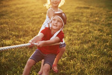 Oğlan ve kız halat çekiyorlar ve parkta çekiştiriyorlar..