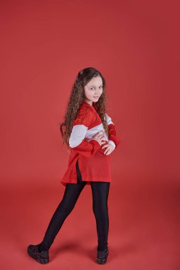Genç ve güzel bir kız kırmızı arka planda dans ediyor, modern ince hip-hop stili genç kız atlıyor..