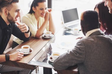 Bir grup girişimci bir dizüstü bilgisayar kullanarak ve bir belge tutarak çalışıyor.