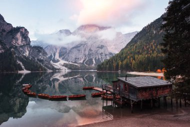 Güneş ışığıyla dolu bulutlar. Dağlarla güzel bir manzara. Ahşap bina ve armudu olan turistik bir yer..