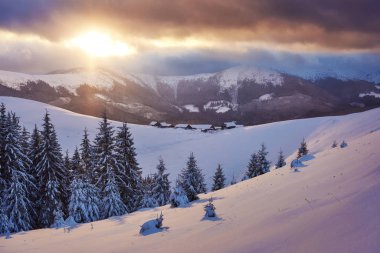 Majestic sunset at small village on a snowy hill under Ukrainian. Villages in the mountains in winter. Beautiful winter landscape. Carpathians, Ukraine, Europe.