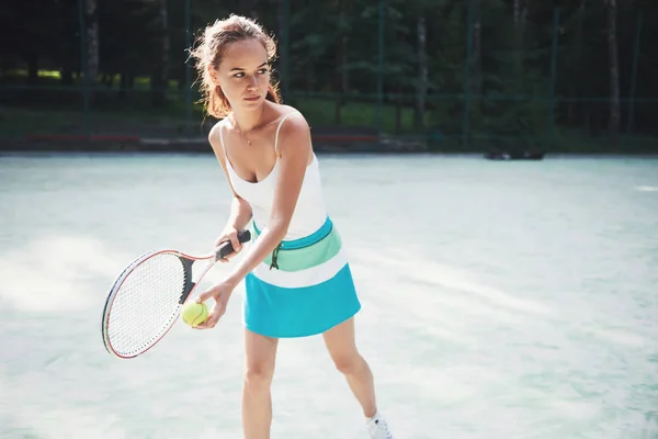 一个漂亮的女人穿着运动服在球场上打网球 — 图库照片