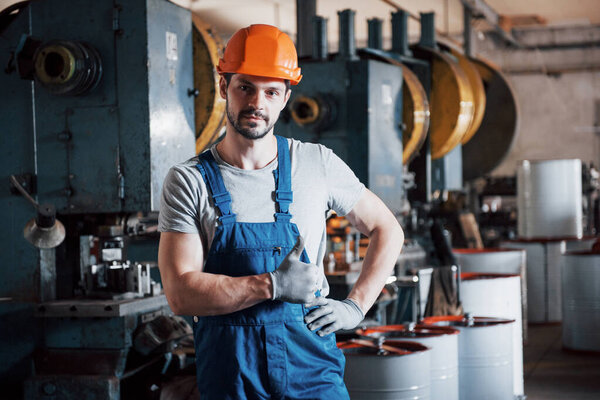 Portrait of a young worker in a hard hat at a large metalworking plant. The engineer serves the machines and manufactures parts for gas equipment.