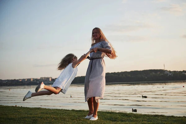 母と娘は湖の近くの草の上で遊ぶ — ストック写真