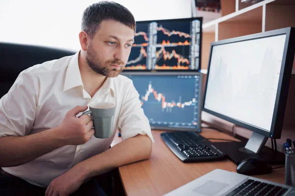 Stockbroker in shirt is working in a monitoring room with display screens. Stock Exchange Trading Forex Finance Graphic Concept. Businessmen trading stocks online.