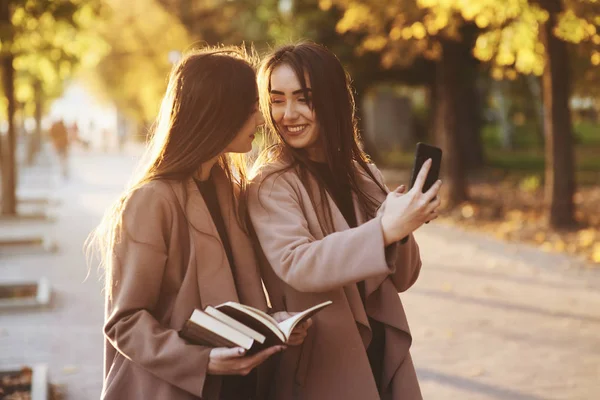 Genç Gülümseyen Esmer Ikiz Kızlar Birbirlerine Bakıp Siyah Telefonlarıyla Selfie — Stok fotoğraf