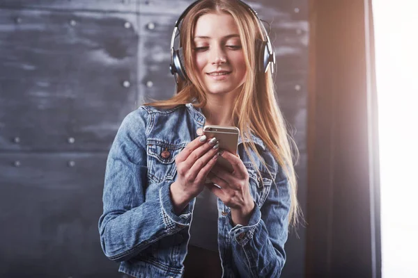 人的概念 紧跟迷人的性感女人与牛仔裤夹克 女孩在演播室里摆姿势 用耳机听音乐 — 图库照片