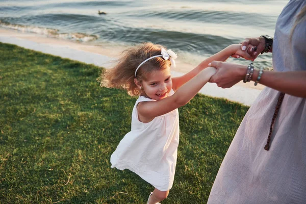 Anne ve küçük kızı gölün kenarındaki çimlerde oynuyorlar.