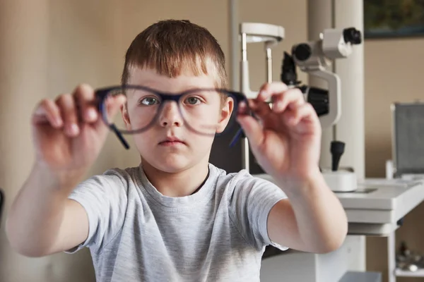 Зосередьтеся Дитині Хлопчик Тримає Окуляри Витягнутих Руках Офтальмологічним Обладнанням Задньому — стокове фото
