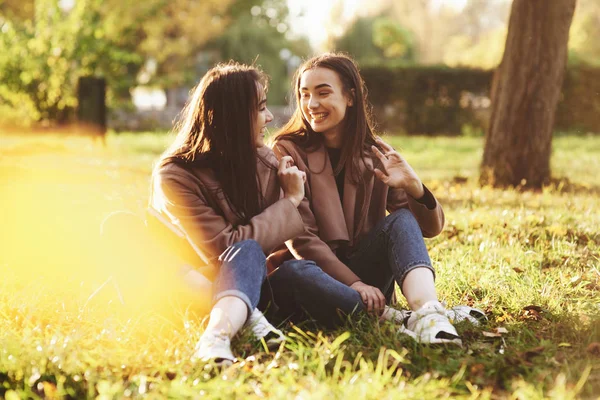 Jonge Glimlachende Brunette Tweeling Meisjes Zitten Gras Met Benen Gekruist — Stockfoto