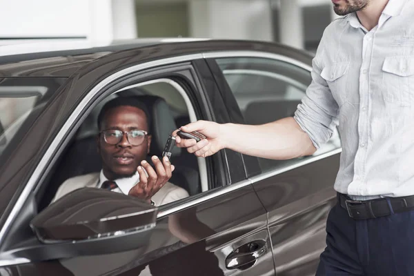 An African American gets keys from a car at a car dealership