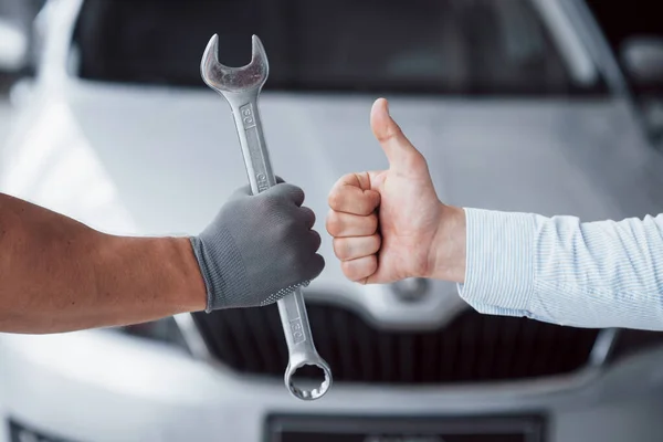 Tamirci anahtarı müşterinin elinde tutuyor ve başparmağını kaldırıyor. Aferin sana..