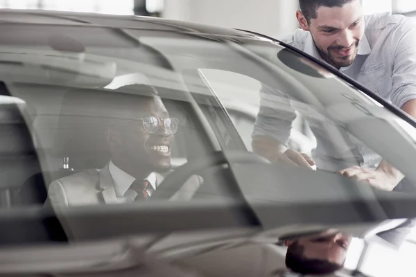 An African man who buys a new car checks a car talking to a professional vendor