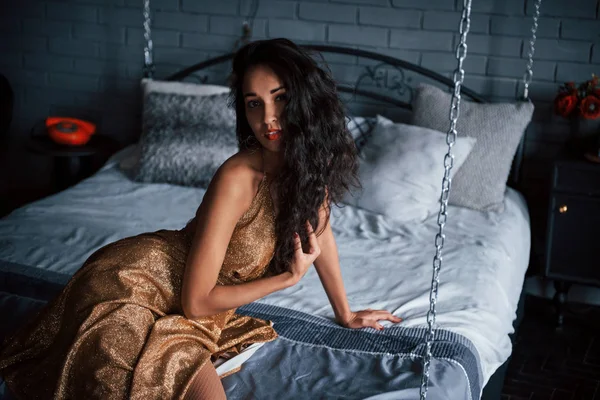 Prachtig Zwart Haar Meisje Gouden Jurk Zit Aan Wit Bed — Stockfoto