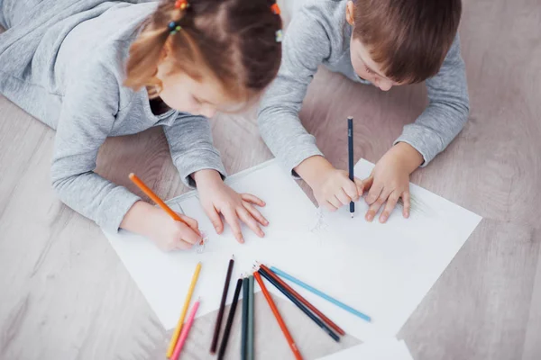 子供たちはパジャマで床に横になり 鉛筆で描く 鉛筆で絵を描く可愛い子 — ストック写真