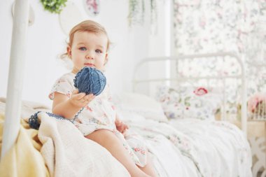 Çocukluk konsepti. Güzel elbiseli bir kız bebek evde oyuncaklarla oynuyor. Beyaz mahsul çocuk odası.