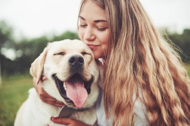 Parkta yeşil çimlerin üzerinde güzel bir köpeği olan güzel bir kızı çerçevelet.