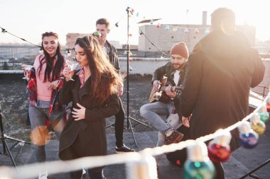Çatıdaki her yerde ampuller var. Genç arkadaşlar hafta sonlarını gitar ve alkolle geçirmeye karar verdiler..