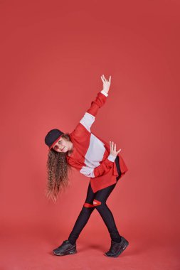 Genç şehir kadını kırmızı arka planda dans ediyor, modern ince hip-hop stili genç kız.