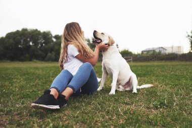 Açık havada köpeği olan çekici genç bir kadın. Labrador Retriever ile yeşil çimlerin üzerinde Gril.