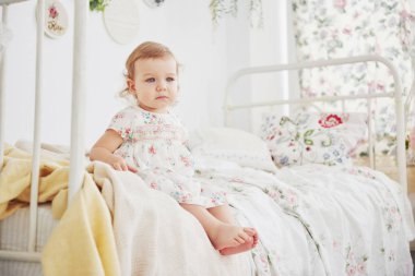 Güzel elbiseli bir kız bebek evde oyuncaklarla oynuyor. Beyaz mahsul çocuk odası. Çocukluk kavramı.