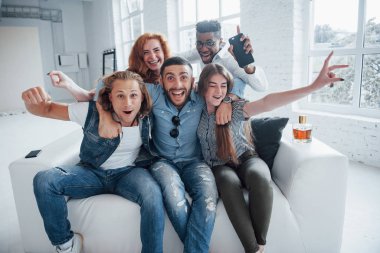 Özgür hissediyorum. Komik genç arkadaşlar beyaz iç kısımda kanepede otururken eğleniyorlar..