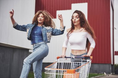 Dışarıda alışveriş yapan iki genç ve mutlu kadın.