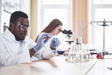 Bilim adamları laboratuarda mikroskopla deney ve analiz yaparak yakından çalışırlar.