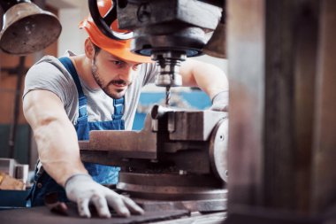Büyük bir atık geri dönüşüm fabrikasında kasketli genç bir işçinin portresi. Mühendis, makinelerin ve diğer ekipmanların çalışmalarını izler..