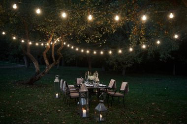 Ampullerden iki sıra. Yemek ve ziyaretçiler için hazırlanmış masa. Akşam vakti..