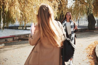 Esmer gider ve gülümser. İki genç arkadaş eğitimden sonra parkta karşılaştıklarına sevindiler..