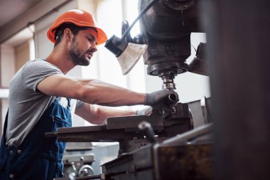 Başlık takmış deneyimli bir operatör. Metal endüstrisi konsepti profesyonel mühendis metal işçisi imalat atölyesinde Cnc değirmen makine merkezi işletiyor.