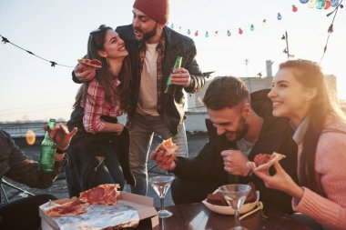 Komik bir şeyden bahsediyordu. Çatıdaki partide pizza yiyorum. İyi arkadaşlar hafta sonları lezzetli yiyecekler ve alkolle vakit geçirir..