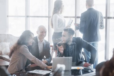 Genç iş arkadaşları modern çalışma ofisinde harika iş görüşmeleri yapıyorlar. Takım çalışması insanları konsepti.