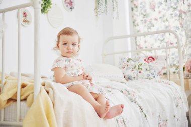 Çocukluk konsepti. Güzel elbiseli bir kız bebek evde oyuncaklarla oynuyor. Beyaz mahsul çocuk odası.