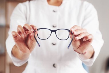 Ön manzara. Kadın eli doktor dolabında mavi gözlük tutuyor..