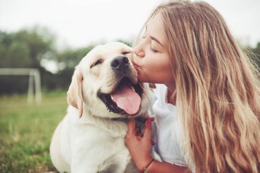Parkta yeşil çimlerin üzerinde güzel bir köpeği olan güzel bir kızı çerçevelet.