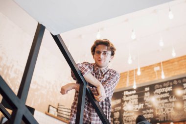 Düşünceli genç adam şekerleme dükkanında oturuyor. Birini beklerken kahve içiyor..