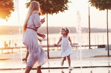 Koşmak ve gülümsemek. Güneşli bir günde anne ve kızı çeşmeyi serinlemek ve onunla eğlenmek için kullanmaya karar verir..