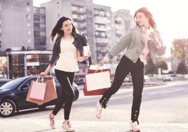 Young attractive girls with shopping bags and coffee in the city.