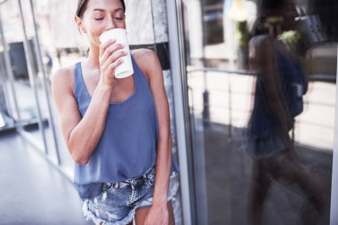 Sokakta yürüyen, şık giyinen, sıcak kahve içen ve gülümseyen genç hippi kadın portresi..