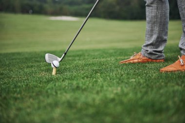 Yeşil bölge golf sahası, beyaz top ve metal sopa. Oyuncu sadece bacakları görebilir..