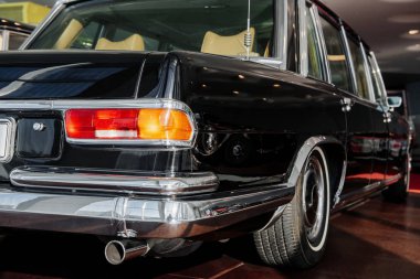 Arka ve yan görünüm siyah retro business class limuzin sağ arka plan ışığı, krom ayna ve tekerlek kemer, kahverengi zemin üzerinde beyaz duvar lastik.