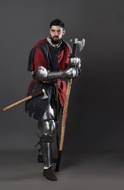 Gri arka planda ortaçağ şövalyesi. Zincirli zırhlı, kırmızı, siyah elbiseli ve savaş baltalı zalim, kirli yüzlü bir savaşçı portresi..