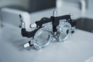 Yandan bir fotoğraf. Beyaz masada duran phoropter 'in detaylı yakın plan fotoğrafı.