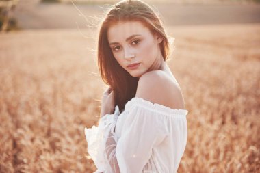 Güneşin altındaki buğday tarlasında mutlu bir genç kız